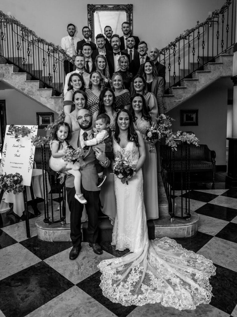Black and white photograph of a wedding party on the hotel staircase