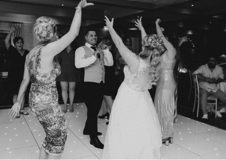 Black and white shot of the bride, groom and guests dancing with arms raised on a starlit dance floor at Roganstown Hotel