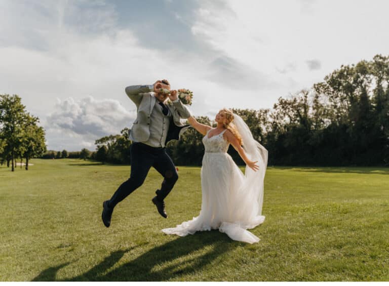 Groom leaping in the air holding the bouquet to his eyes as the bride laughs on the golf course at Roganstown Hotel