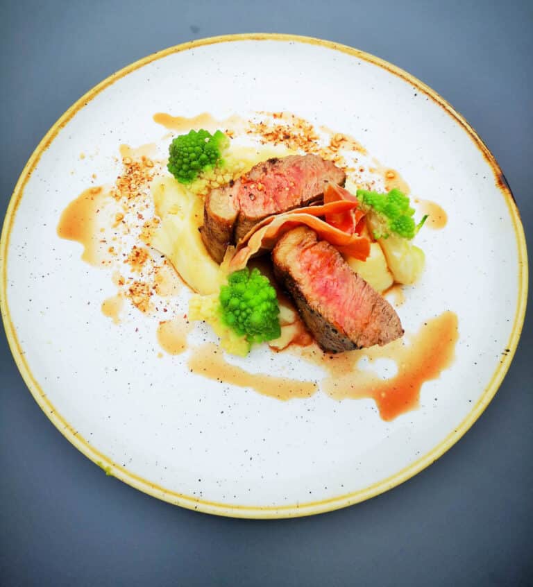 Sliced medium-rare beef with creamy mash, romanesco, crispy ham and jus at Roganstown Hotel